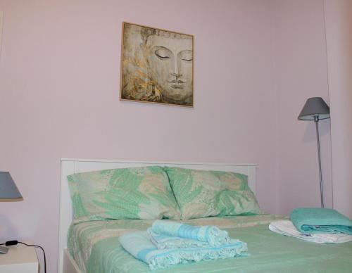 Una cama con toallas en ella con una foto en la pared en SERENITY yard apartment en Poros