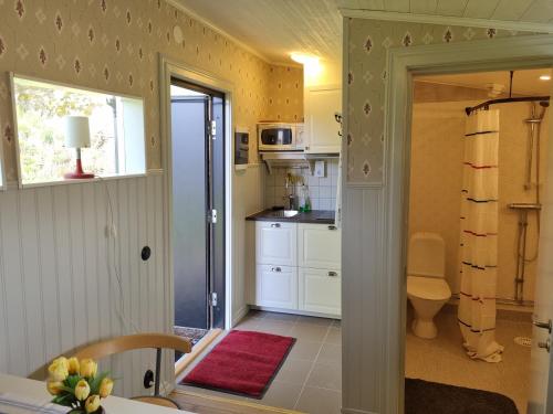 eine Küche mit weißen Schränken und einem roten Teppich in der Unterkunft Korskullens Stugor in Söderköping
