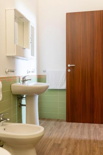 a bathroom with a sink and a toilet and a wooden door at Oltre il Mare Trabia in Trabia