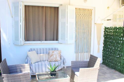 eine Veranda mit Stühlen, einem Sofa und einem Fenster in der Unterkunft SERENITY yard apartment in Poros