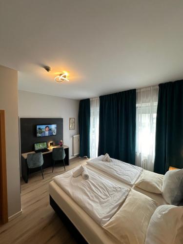 Schlafzimmer mit einem großen weißen Bett und einem Schreibtisch in der Unterkunft Hotel Stadt Emmerich in Emmerich
