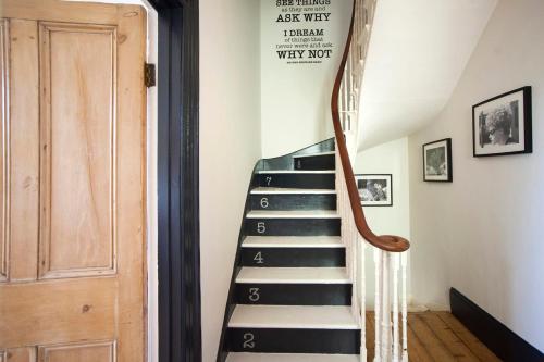 un escalier dans une maison avec un panneau sur le mur dans l'établissement higgihaus 7 Bed Sleeps up to 18 Big Groups Best Location, à Bristol