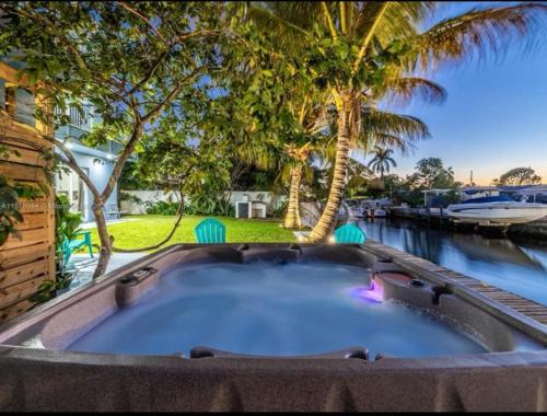 a large jacuzzi tub in a backyard with palm trees at Hot Tub! Roof Top! Firepit! Boat Dock! in Fort Lauderdale