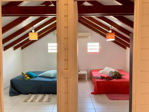 two beds in a room with vaulted ceilings at Maison SELAH F3 Piscine Jardin Privatif Citerne in Le Moule