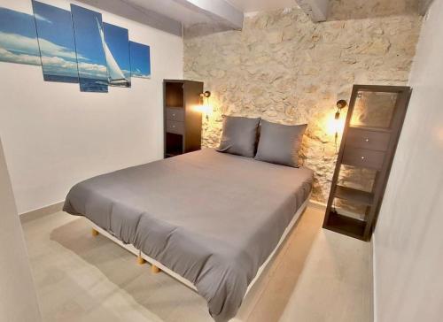 un lit dans une chambre avec un mur en pierre dans l'établissement Grand T5 avec patio et Sauna à 5mn à pied de la Plage des Catalans, à Marseille