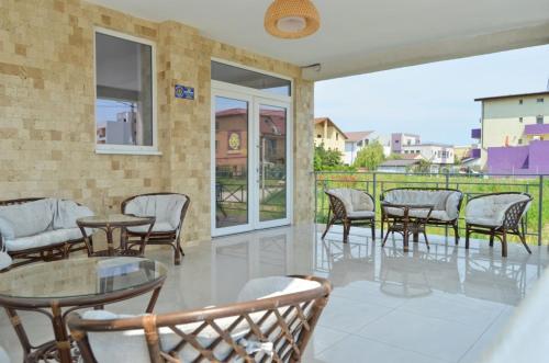 patio con mesas y sillas y balcón en Abi Mykonos, en Mamaia Nord – Năvodari