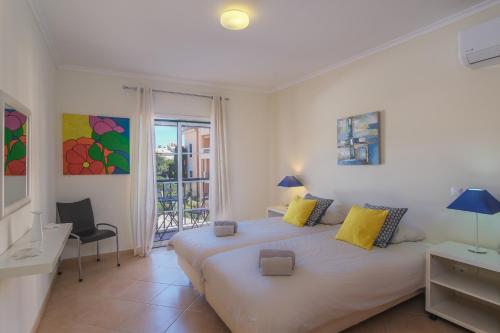 um quarto com uma grande cama branca com almofadas amarelas em Luz casas-St James 215, 3 bedrooms,wi fi, air con,shared pool na Praia da Luz