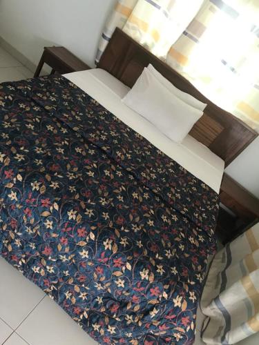 a bed with a floral comforter on top of it at Paradialaw in Rufisque
