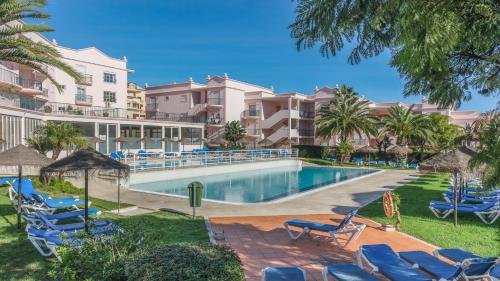 uma piscina com cadeiras azuis e palmeiras em Luz casas-St James 215, 3 bedrooms,wi fi, air con,shared pool na Praia da Luz