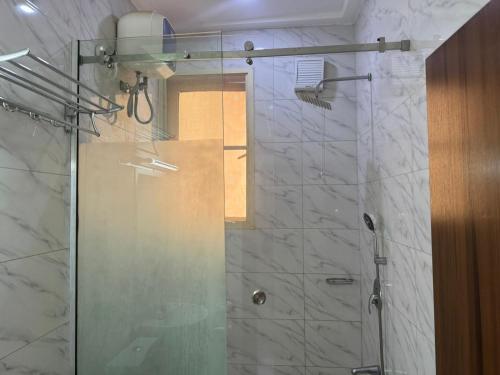 um chuveiro com uma porta de vidro na casa de banho em Sugarland Hotel and Suite em Ikeja