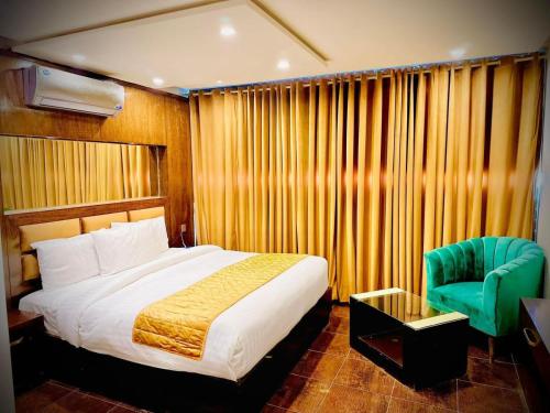 um quarto com uma cama e uma cadeira verde em Bling International Hotel Multan em Multan