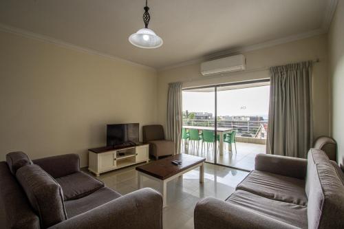 een woonkamer met banken, een televisie en een balkon bij Saints View Resort Unit 17 in Uvongo Beach