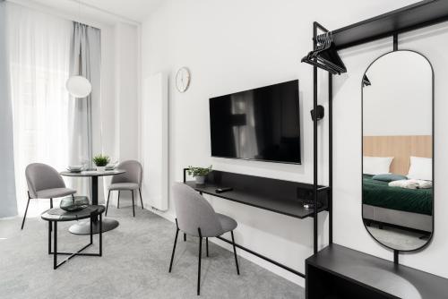 CityCenter Sauna & Fitness Apartments Podgórna by Renters Prestige في بوزنان: غرفة معيشة فيها تلفزيون وطاولة وكراسي