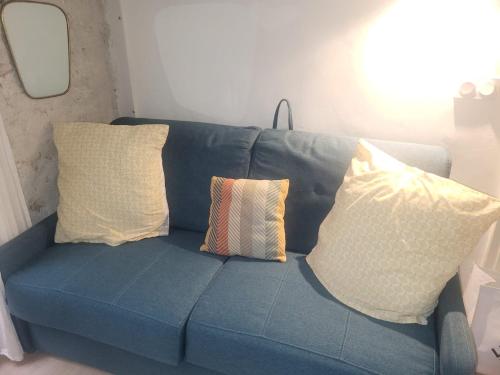 eine blaue Couch mit Kissen darauf in einem Zimmer in der Unterkunft Studette Rémilly à Versailles in Versailles