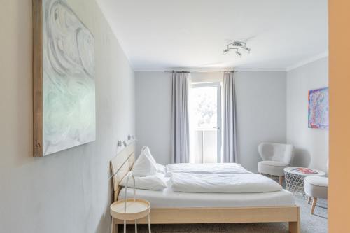 a white bedroom with a bed and a window at Hotel Jakob in Fuschl am See