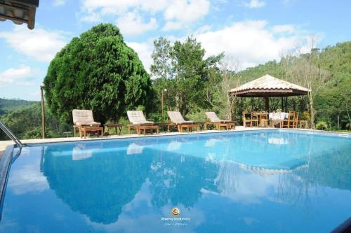 einen großen Pool mit Stühlen und einem Pavillon in der Unterkunft Sítio Vale da Colina-Nazaré Paulista - 6 pessoas in Nazaré Paulista