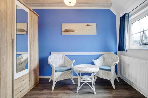 a room with two chairs and a table and a blue wall at Ferienhaus Seepferdchen in Dranske