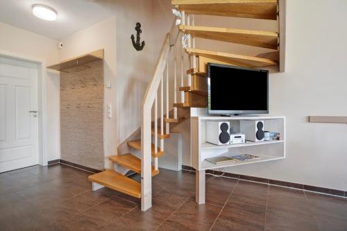a living room with a staircase with a flat screen tv at Ferienhaus Seepferdchen in Dranske