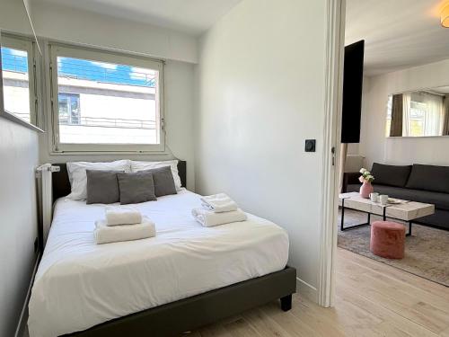 une chambre avec un lit avec des draps blancs et une fenêtre dans l'établissement L'appartement Bouquet, à Paris