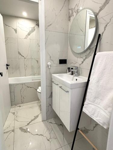 une salle de bain blanche avec un lavabo et un miroir dans l'établissement L'appartement Bouquet, à Paris