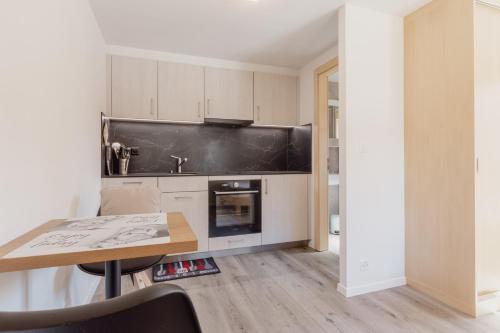 una cucina con mobili bianchi e un tavolo di legno di Studio à 2 minutes des remontées mécaniques a Grimentz