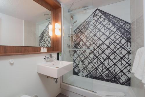 La salle de bains est pourvue d'un lavabo et d'un miroir. dans l'établissement Campanile Taverny, à Taverny