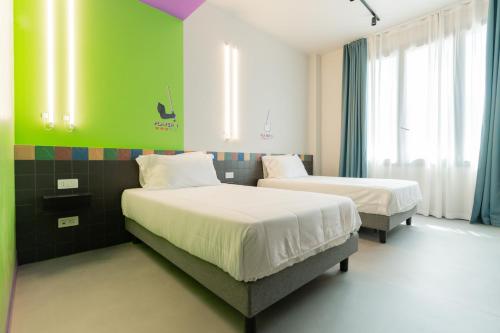 a room with two beds and a green wall at The Match Hotel in Cervia