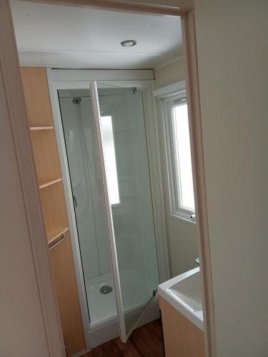 La salle de bains est pourvue d'une douche et d'un miroir en verre. dans l'établissement camping soleiluna, à Herm