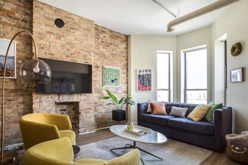 a living room with a couch and a brick wall at Beautifully Remodeled Third Floor Flat in River North - 3N in Chicago