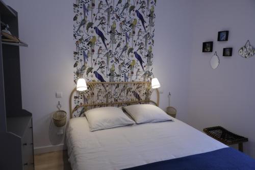 een slaapkamer met een bed met een gedessineerd hoofdeinde bij la maison aux oiseaux in Lanvallay