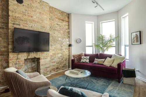 a living room with a couch and a brick wall at Beautifully Remodeled Second Floor Flat in River North - 2N in Chicago