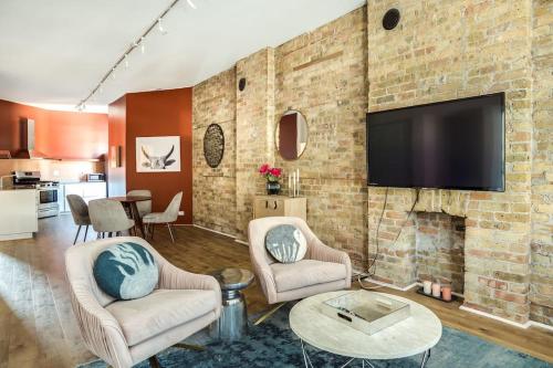 a living room with a brick wall with a flat screen tv at Beautifully Remodeled Second Floor Flat in River North - 2N in Chicago