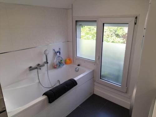 La salle de bains blanche est pourvue d'une baignoire et d'une fenêtre. dans l'établissement Charmante maison de ville, au Mans