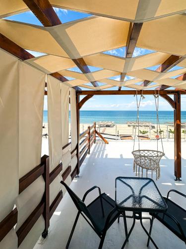porche con sillas y vistas a la playa en Deos Suites, en Neoi Poroi