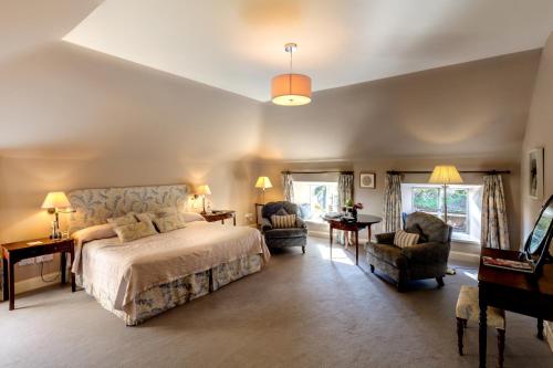a bedroom with a large bed and two chairs at Ballymaloe House Hotel in Ballycotton