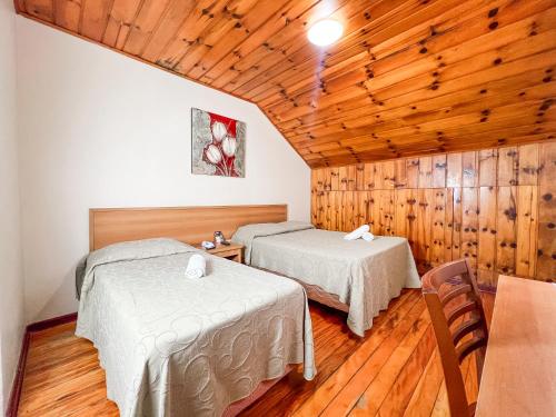two beds in a room with wooden walls at Hotel Fazenda Golden Park Campos do Jordão in Campos do Jordão