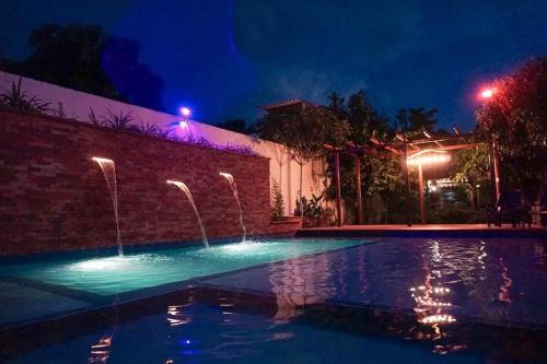 a swimming pool with a fountain at night at Villa Cabana Inn in Playa Dormida