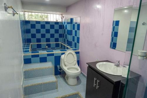 a blue and white bathroom with a toilet and a sink at Villa Cabana Inn in Playa Dormida