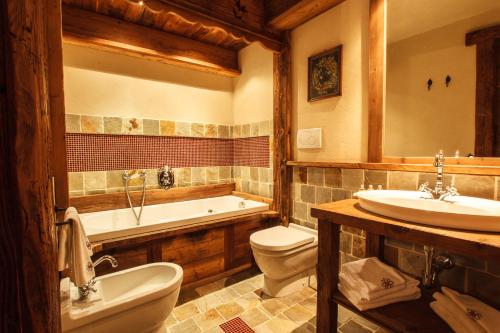 a bathroom with a tub and a toilet and a sink at Au Coeur Des Neiges Resort SPA & FREE E-BIKE in Courmayeur