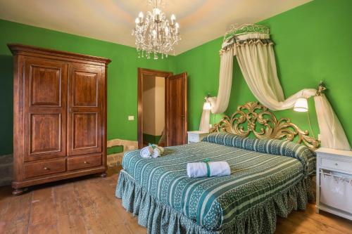 Un dormitorio con una cama con paredes verdes y una lámpara de araña. en BASILIMO di Home Hill, en Capannori