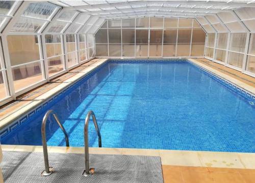 a large indoor swimming pool with blue water at Los Castelos by Urraca Suites Viveiro in Viveiro