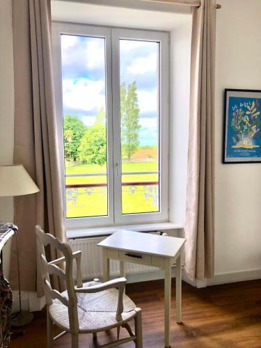 une table et une chaise devant une fenêtre dans l'établissement La Maison du Hommeel, à Gratot
