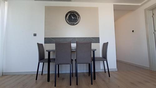 a dining room table with chairs and a clock on the wall at 19th & 18th Floor Secure Apartments with Pool & Fitness & Parking included in price in Skopje