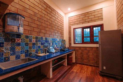 a kitchen with blue tiles on the wall and a sink at Phoenix Holiday Home in Kanyakumari
