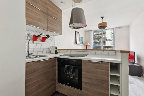 une cuisine avec des armoires en bois et un évier dans l'établissement Appartement cosy proche porte maillot, à Neuilly-sur-Seine