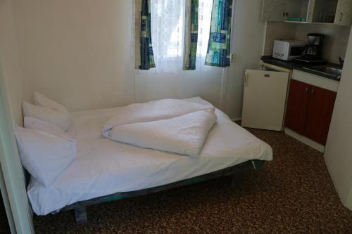 Tulipán Camping في جينيسدياس: سرير بشرشف ووسائد بيضاء في الغرفة