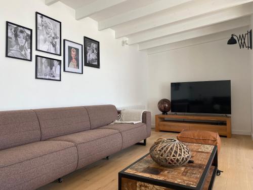 Vakantiehuis Zand7 في لوميل: غرفة معيشة مع أريكة وتلفزيون بشاشة مسطحة