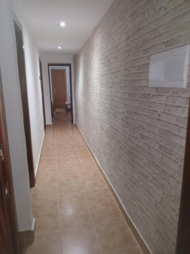 pasillo con pared de ladrillo y suelo de baldosa en Habitación Higuera, en Lumpiaque