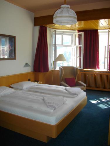 a bedroom with a large bed and a chair at Hotel Villa Emilia in Ortisei