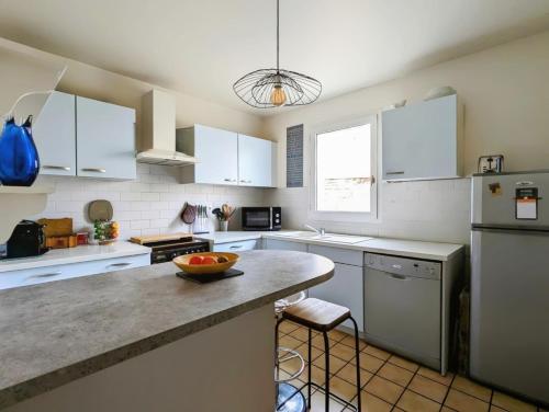 une cuisine avec des armoires blanches et un bol de fruits sur un comptoir dans l'établissement Duplex T2 Bords de Seine, à Meulan-en-Yvelines